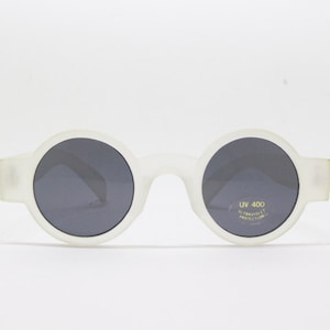 May include: White round sunglasses with dark gray lenses. The sunglasses have UV 400 ultraviolet protection printed on the right lens.