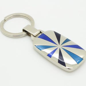 Vintage rectangular steel key ring made in England. Substantial solid metal base with enamelled sunburst pattern in blue tones. NOS