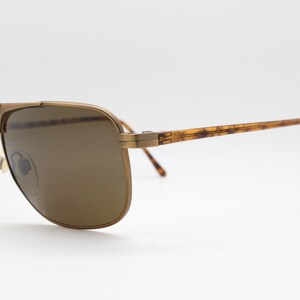 May include: Gold-tone aviator sunglasses with brown lenses and tortoise shell arms.