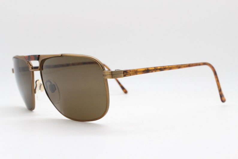 May include: Gold-tone aviator sunglasses with brown lenses and tortoise shell arms.