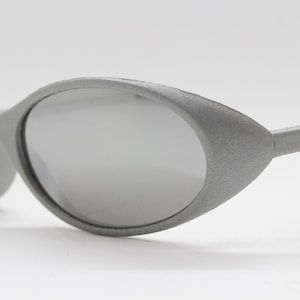 May include: Silver-toned sunglasses with a cat-eye shape and a textured finish.