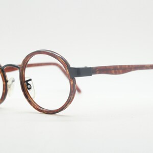 May include: Round tortoiseshell eyeglasses with black metal arms.