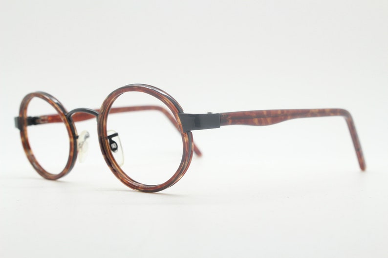 May include: Round tortoiseshell eyeglasses with black metal arms.