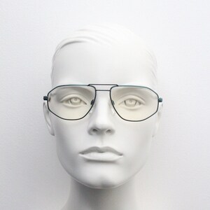 May include: A white mannequin head wearing a pair of black and teal aviator sunglasses with clear lenses.