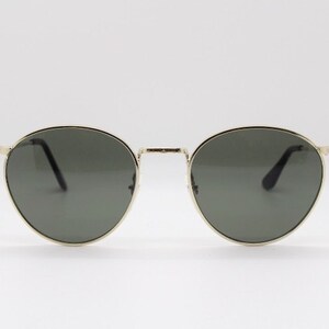 Pu&ograve; includere: Occhiali da sole rotondi con montatura in metallo dorato e lenti grigio scuro. Il design &egrave; classico. Le lenti grigio scuro offrono protezione solare. Un accessorio elegante.