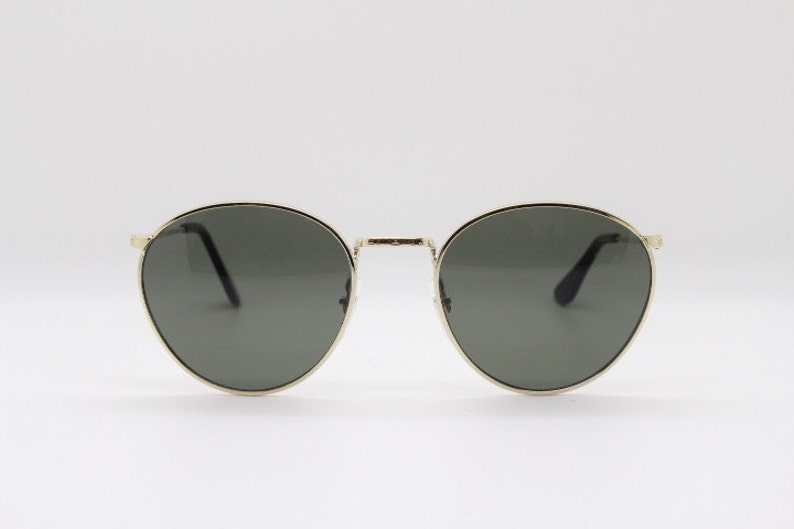 Pu&ograve; includere: Occhiali da sole rotondi con montatura in metallo dorato e lenti grigio scuro. Il design &egrave; classico. Le lenti grigio scuro offrono protezione solare. Un accessorio elegante.