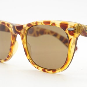 Sunburst vintage 80s wayfarer design sunglasses. All time classic design in amber mottled frame with Havana brown lenses.  Unused NOS