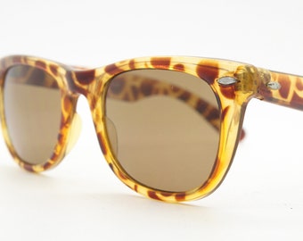Sunburst vintage 80s wayfarer design sunglasses. All time classic design in amber mottled frame with Havana brown lenses.  Unused NOS