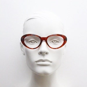 Op de afbeelding: Een paar bruine schildpad-ovale brillen met heldere glazen.