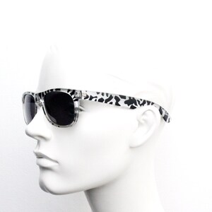 May include: White sunglasses with black and white animal print frames and dark lenses.