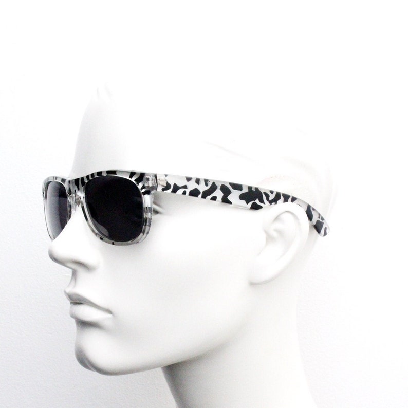 May include: White sunglasses with black and white animal print frames and dark lenses.
