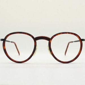 Puede incluir: Gafas redondas de carey con montura de metal.