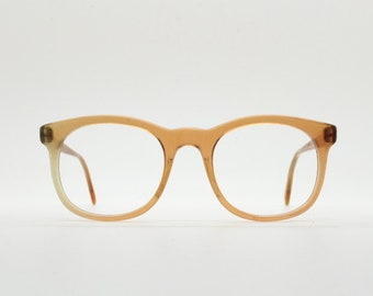 Puede incluir: Un par de gafas redondas de color ámbar con lentes transparentes.