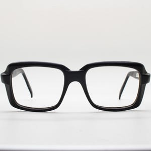 May include: Black plastic framed eyeglasses with square lenses.