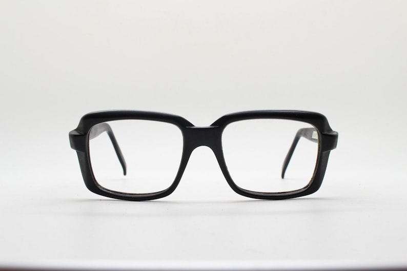 May include: Black plastic framed eyeglasses with square lenses.
