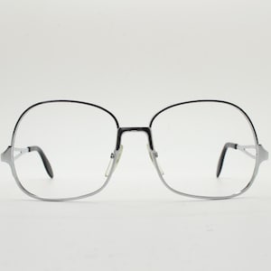 May include: Silver-rimmed glasses with a black frame and clear lenses.