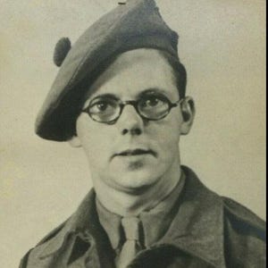 May include: A vintage black and white portrait of a person wearing a beret, round glasses, and a military uniform. The beret has a small, rounded detail on top. The person is looking directly at the camera.