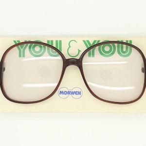 May include: Brown-framed spectacles with large, square lenses, presented on a cream-coloured card. The card displays the text "YOU & YOU" in green and the brand name "MORWEN" in a blue circle. The spectacles have a retro design.
