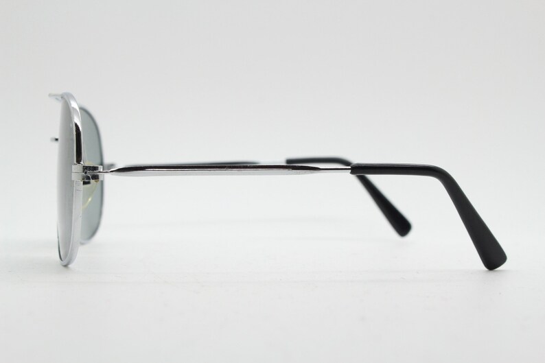 May include: Silver aviator sunglasses with black arms. The sunglasses have a mirrored lens.