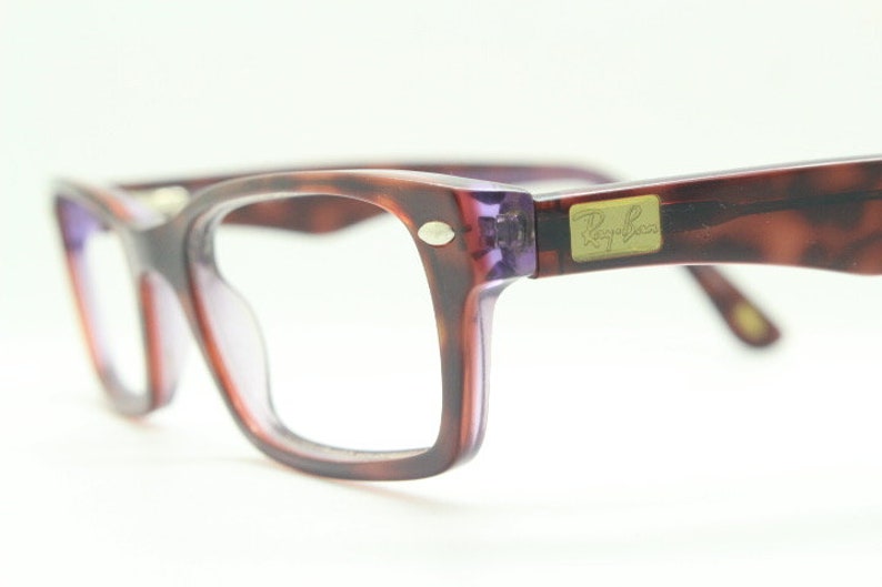 May include: A pair of tortoiseshell Ray-Ban spectacles with purple frames and clear lenses.