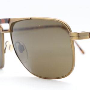 May include: Gold-tone aviator sunglasses with brown lenses and tortoise shell accents on the arms.