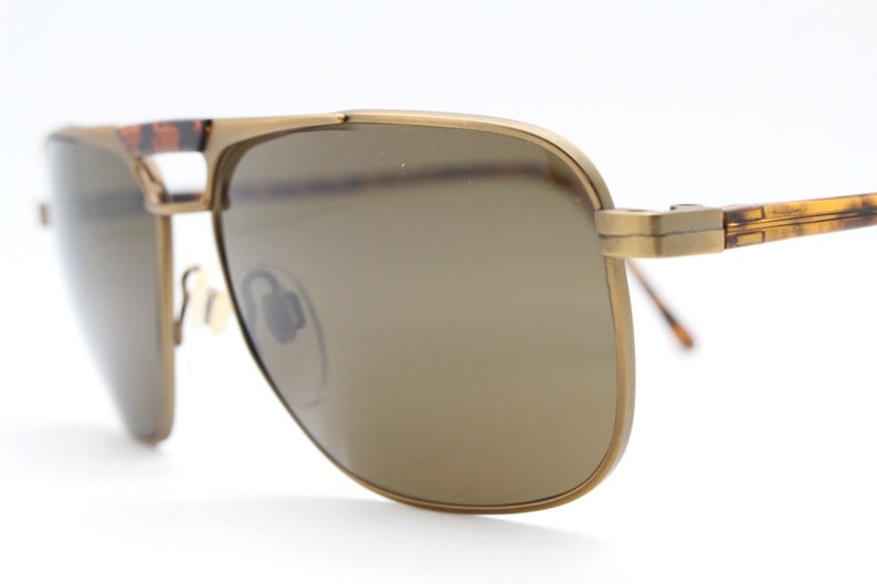 May include: Gold-tone aviator sunglasses with brown lenses and tortoise shell accents on the arms.