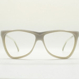 May include: White plastic framed eyeglasses with a cat-eye shape.