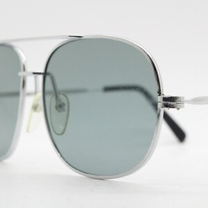 May include: Silver aviator sunglasses with gray lenses. The sunglasses have a metal frame and are in focus.