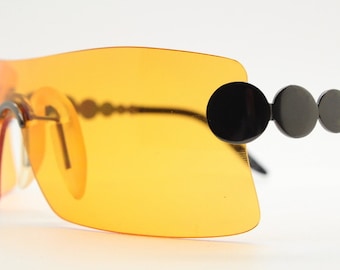 Y2K vintage visor sunglasses. Blazing orange frameless mono lens shield with gunmetal circle chain arms. 2000's mini mask cosplay
