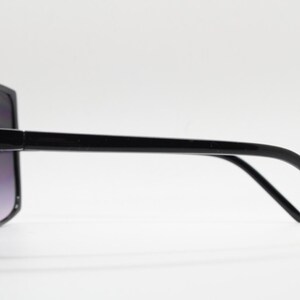 Puede incluir: Gafas de sol negras de gran tama&ntilde;o con montura cuadrada y patillas finas.