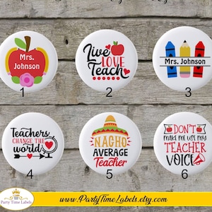 May include: Set of six 2.25 inch round teacher themed buttons with various designs. The designs include: "Mrs. Johnson" with an apple, "Live Love Teach" with an apple, "Mrs. Johnson" with crayons, "Teachers Change the World" with a heart, "Nacho Average Teacher" with a sombrero, and "Don't Make Me Use My Teacher Voice" with a megaphone.