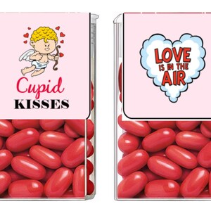 May include: Two clear plastic containers filled with red candy hearts. The container on the left has a pink label with a cartoon cupid and the text "Cupid Kisses". The container on the right has a pink label with a red heart and the text "Love is in the air".