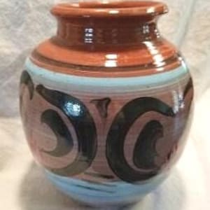 May include: A rounded ceramic vase with a wide neck and a glossy finish. The body features a terracotta base color decorated with horizontal light blue bands and large, dark brown, swirling abstract patterns painted around the center.
