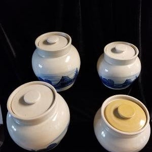 May include: Set of four ceramic canisters with blue and white painted designs. The canisters have lids and are in various sizes.