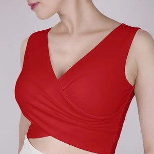 Könnte beinhalten: Ein rotes, ärmelloses Crop-Top mit V-Ausschnitt und einem Kreuzdesign auf der Vorderseite.