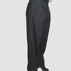 May include: Black pinstripe pants with a wide leg and a high waist. The pants are made of a smooth, lightweight fabric and have a classic, tailored look.