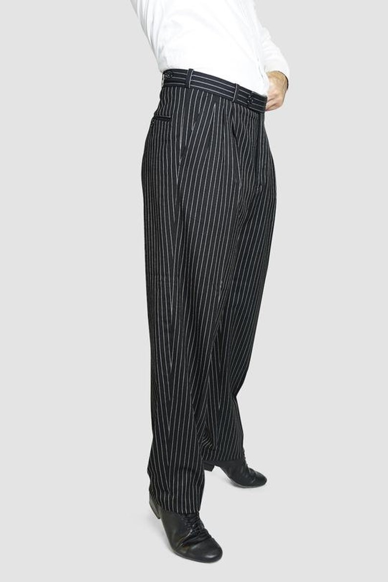 May include: Black pinstripe pants with a wide leg and a high waist. The pants are made of a smooth, lightweight fabric and have a classic, tailored look.