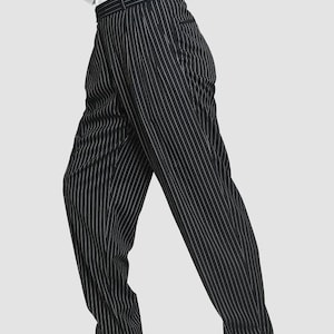 May include: Black pinstripe pants with a white stripe. The pants have a high waist and a wide leg.