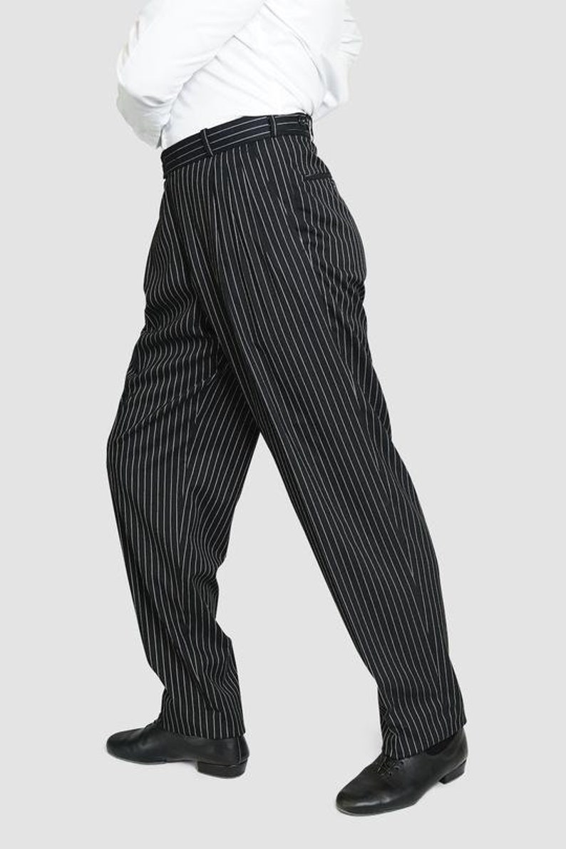 May include: Black pinstripe pants with a white stripe. The pants have a high waist and a wide leg.