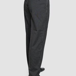 May include: Black pinstripe pants with a white stripe. The pants have a belt loop and a back pocket. The pants are worn with black shoes.