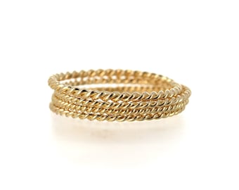 May include: Four gold-toned, braided rings stacked on top of each other. The rings are all the same size and have a smooth, polished finish.