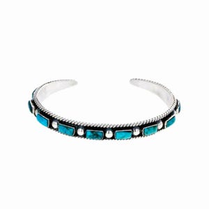 May include: A silver bracelet with turquoise stones set in a silver band. The bracelet is a simple design with a delicate look.