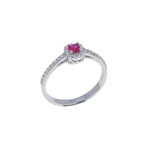 May include: A silver ring with a red gemstone surrounded by smaller white gemstones. The ring has a delicate band with a row of small white gemstones.