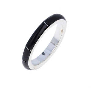 May include: A silver band ring with a black and white inlay. The ring is thin and has a simple design.
