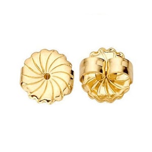 May include: A pair of gold-toned earring backs. The backs are round with a swirl design and a small hole in the center. The backs have a hinged closure.