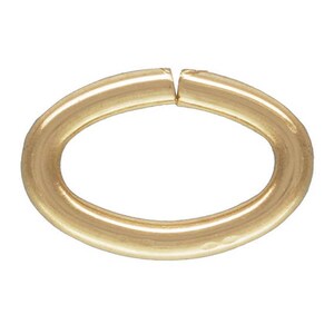 May include: A gold-colored oval jump ring, a type of jewelry finding used for connecting chains, cords, or other jewelry components.