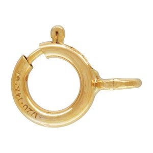 May include: A close-up of a gold-colored spring ring clasp. The clasp is round with a hinged opening and a small lever. The metal is stamped with "1/20 14K GF".