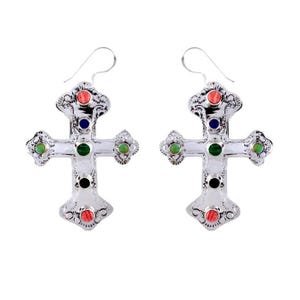 May include: A pair of silver cross earrings with colorful stones. The earrings feature a silver cross with green, blue, black, and red stones.