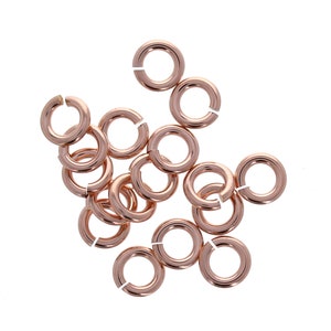 May include: A group of 15 rose gold jump rings, each with a diameter of approximately 6mm. These rings are ideal for jewelry making and crafting.