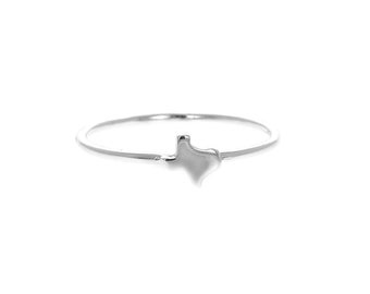 May include: A silver ring with a small, raised outline of the state of Texas.